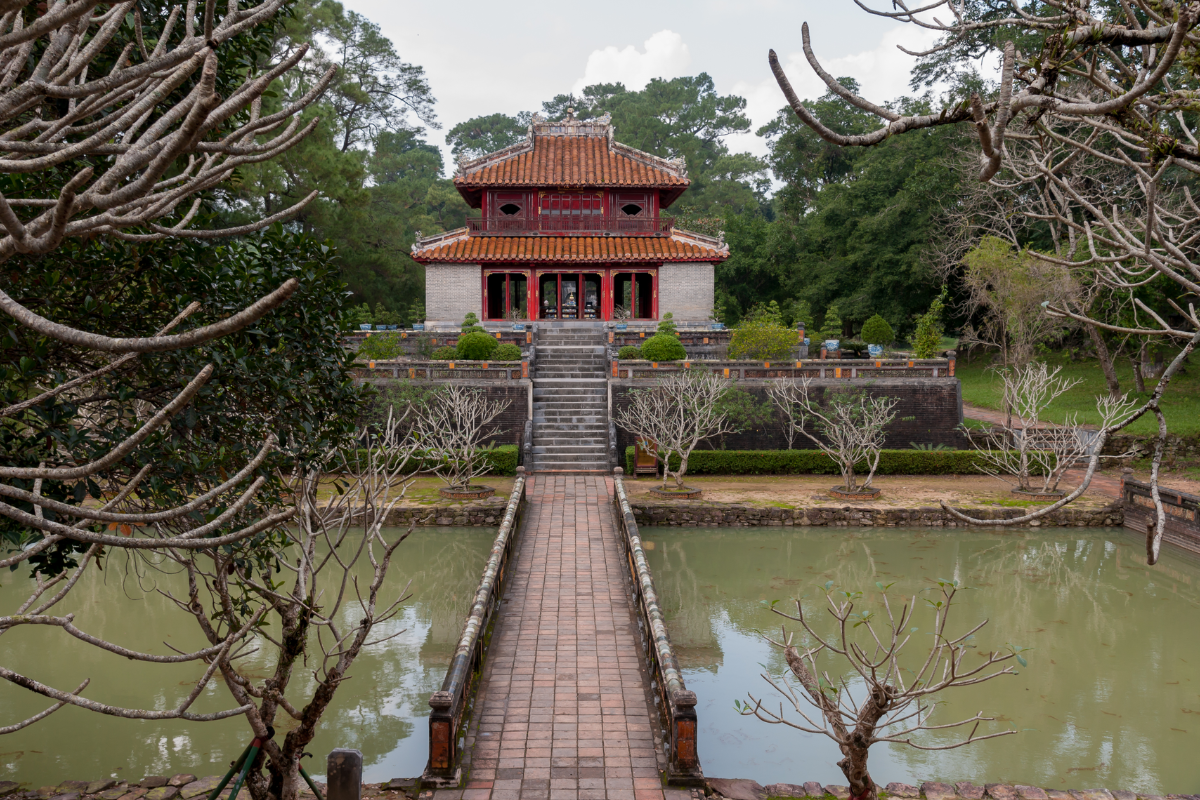 Peaceful lake and bridge at Minh Mang Tomb surrounded by greenery